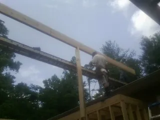 Carpenter setting a ridge beam over a new addition frame — Ice Dam Removal by Roofing Brothers in Ruby