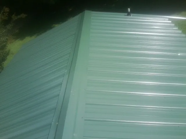 New green metal panels meeting at the ridge of a roof — Flat Roof Repair work by our crew in Ruby